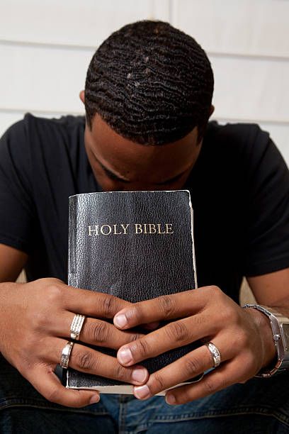 Man Sitting On The Couch Holding His Bible While Praying