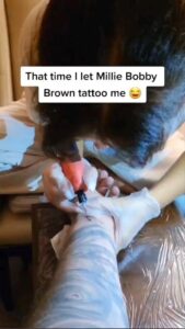 Millie Bobby Brown tattooing “011” to Gordon James. Images